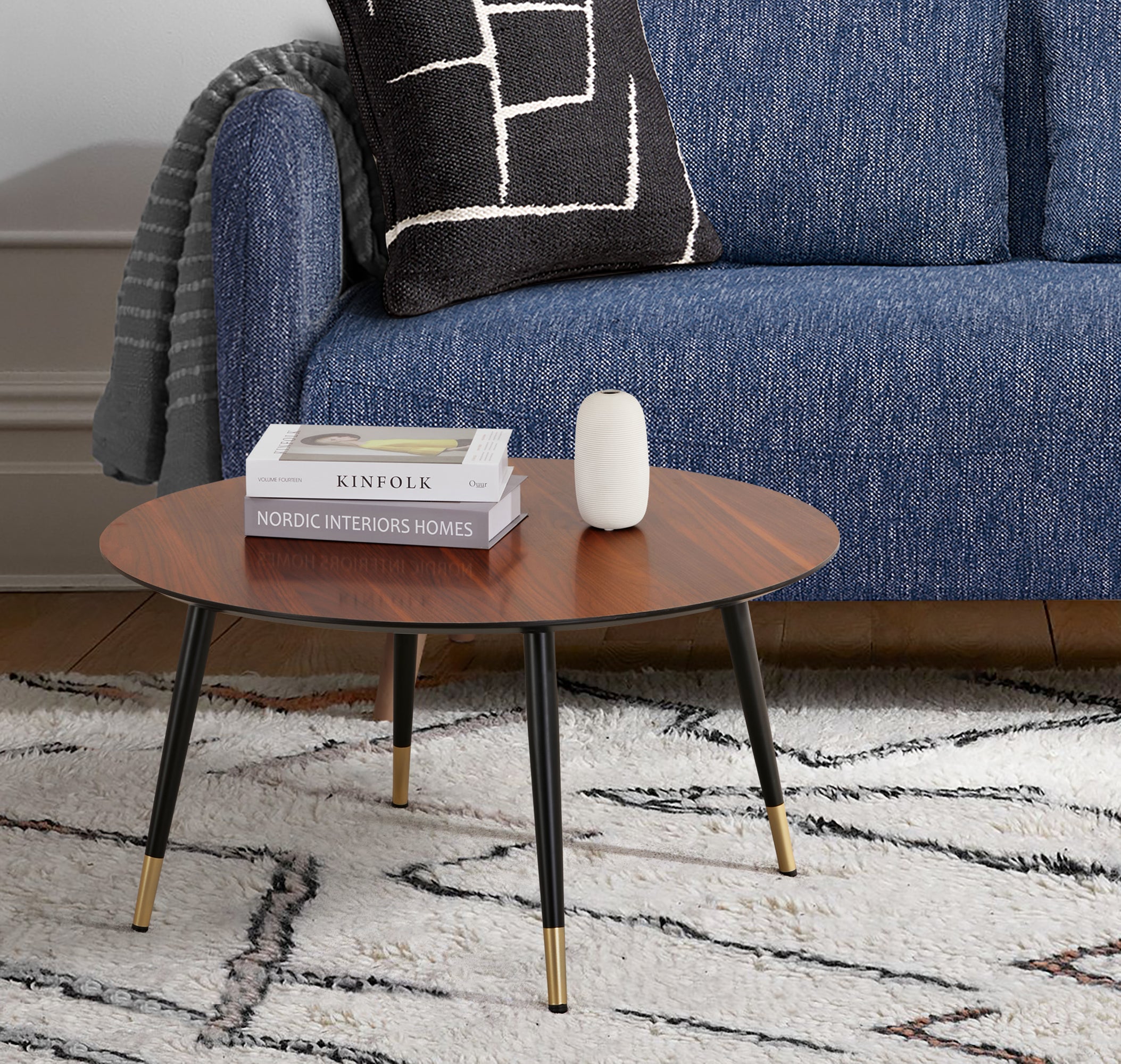 Vue d’ambiance de la table basse ronde MATIS diamètre 80 cm en finition mélaminé imitation noyer avec le canapé-lit BZ ARI en finition bleue jean